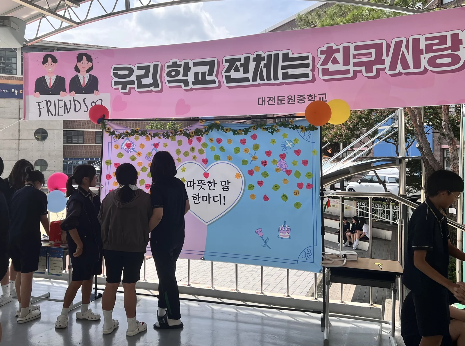따뜻한 말이 적힌 메모지로 꾸민 언어폭력 예방 포토존의 학생 참여 모습